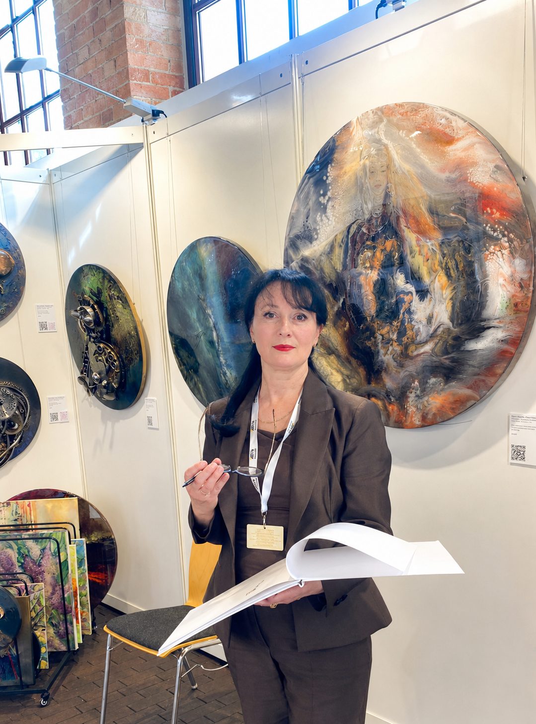 Irina Gerhardt at an exhibition booth in Stuttgart surrounded by her artworks